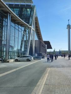 Leute laufen vor großem aus Glas und Stahlstreben bestehendem Gebäude