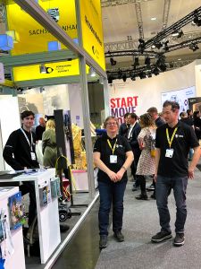 drei Personen stehen neben Messestand